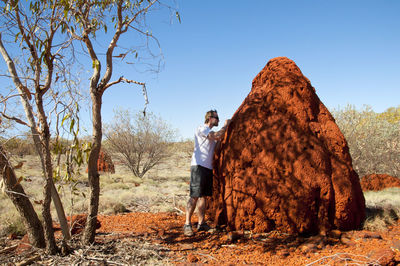 Man standing by rock against clear sky