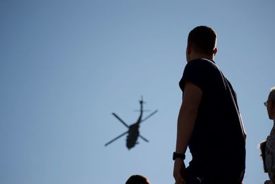 Rear view of men standing against clear blue sky