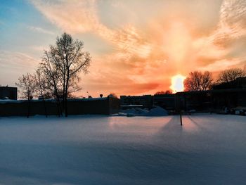 Snow covered landscape against sky during sunset