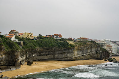 Buildings by sea against clear sky