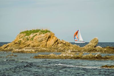 Sailboat on rock by sea against sky