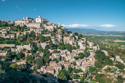 Aerial view of buildings in town against blue sky