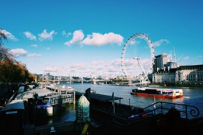 Ferris wheel at harbor against sky in city