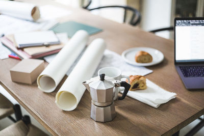 High angle view of teapot with documents rolled up on table