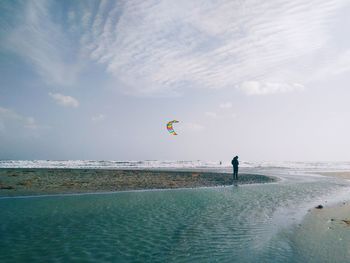 Person paragliding over sea against sky