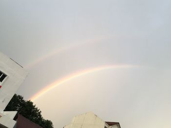 Low angle view of rainbow over building against sky