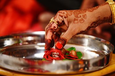 Cropped hand of woman with henna tattoo putting religious offering in plate