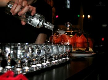 Close-up of man pouring alcohol in glasses on bar counter