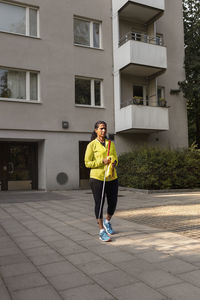 Visually impaired woman standing in front of block of flats