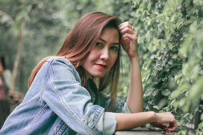 Portrait of young woman against plants