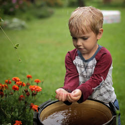 Cute little boy gathering a rain water into his hands, water economy concept