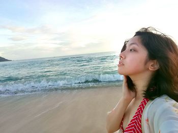 Close-up of young woman at beach against sky