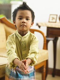 Portrait of boy gesturing while standing at home