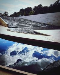 Reflection of trees in swimming pool against sky