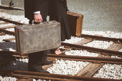 Low section of business colleagues holding suitcases while standing on railroad tracks