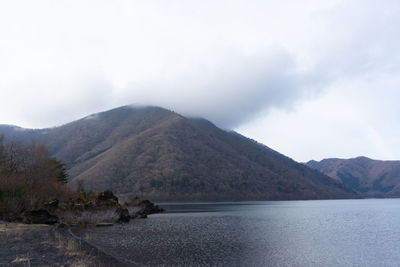 Scenic view of mountain by sea against sky