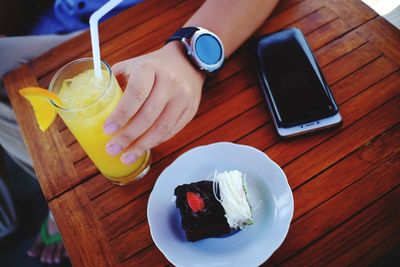 Cropped image of woman holding coffee cup on table