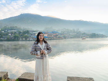Young woman standing against lake