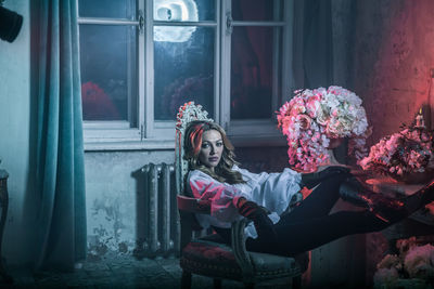 Portrait of woman in costume sitting on chair at home during night