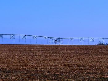 Electricity pylon on field against clear sky