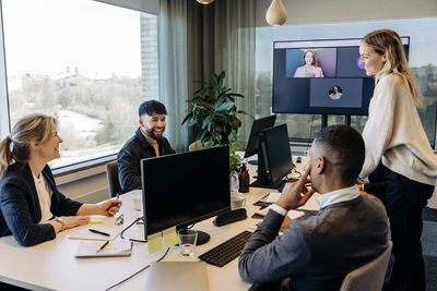 Happy business colleagues discussing with each other in conference room at office