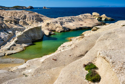 Scenic view of rocks on sea shore against sky