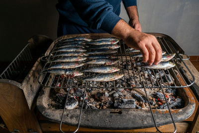 High angle view of man preparing fish on barbecue grill