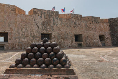 Full frame view of cannon balls in a courtyard of a fortress with flags above walls on a sunny day