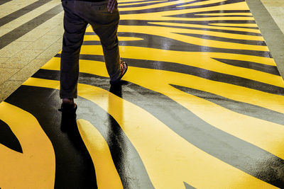 Low section of man walking on patterned zebra crossing