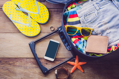 High angle view of mobile phone with suitcase on table