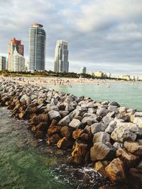 Sea by modern buildings against sky