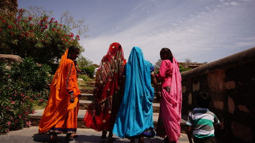 Rear view of women with boy walking on steps against sky