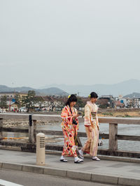 People standing on mountain against clear sky