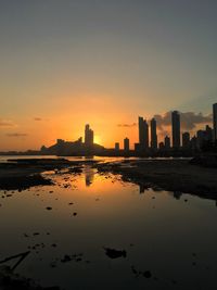 Scenic view of silhouette city by buildings against sky during sunset