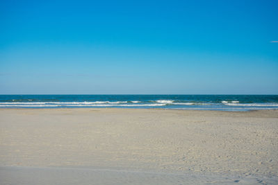 An empty beach and ocean with a clear blue sky behind at wildwood new jersey