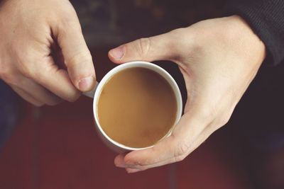 High angle view of hands holding coffee cup