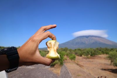 Midsection of person holding ice cream against sky