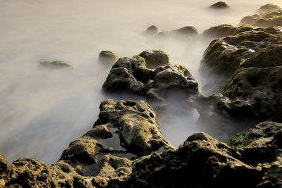 Scenic view of rocks on sea against sky