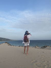 Traveler woman standing on beach against sky