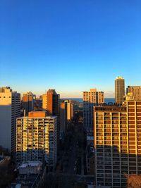 Modern buildings in city against clear blue sky