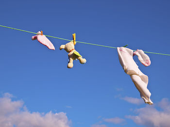 Low angle view of clothespins on rope against blue sky