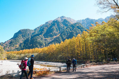 Rear view of people walking on mountain against clear sky