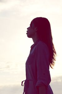 Side view of a young man looking away against sky