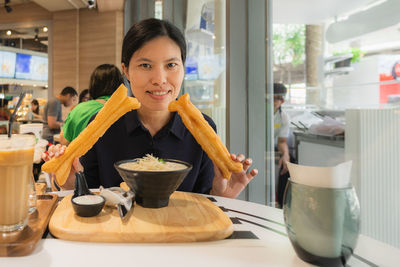 Portrait of a smiling young woman having food in restaurant