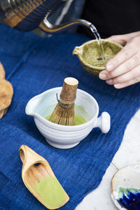 Freshly homemade matcha green tea and a traditional bamboo whisk for whipping matcha powder.