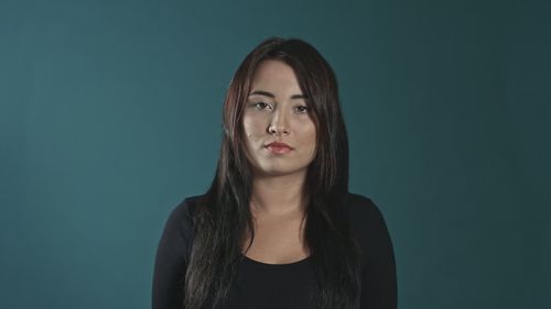 Portrait of young woman against gray background