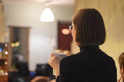 Rear view of woman holding coffee cup