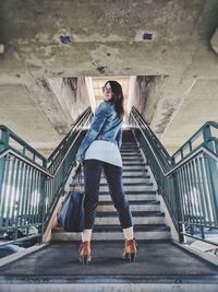 Full length portrait of young woman standing on stairs