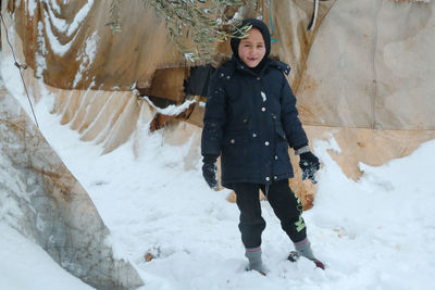 Portrait of young woman standing on snow covered landscape