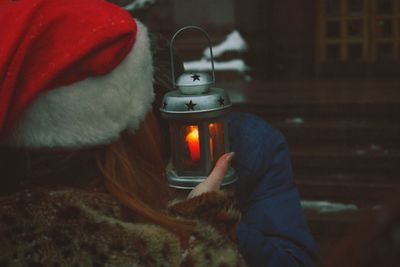 Rear view of woman holding illuminated lantern with friend during winter